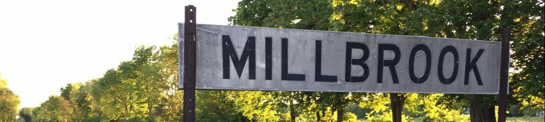 Millbrook Sign Next to Train Tracks